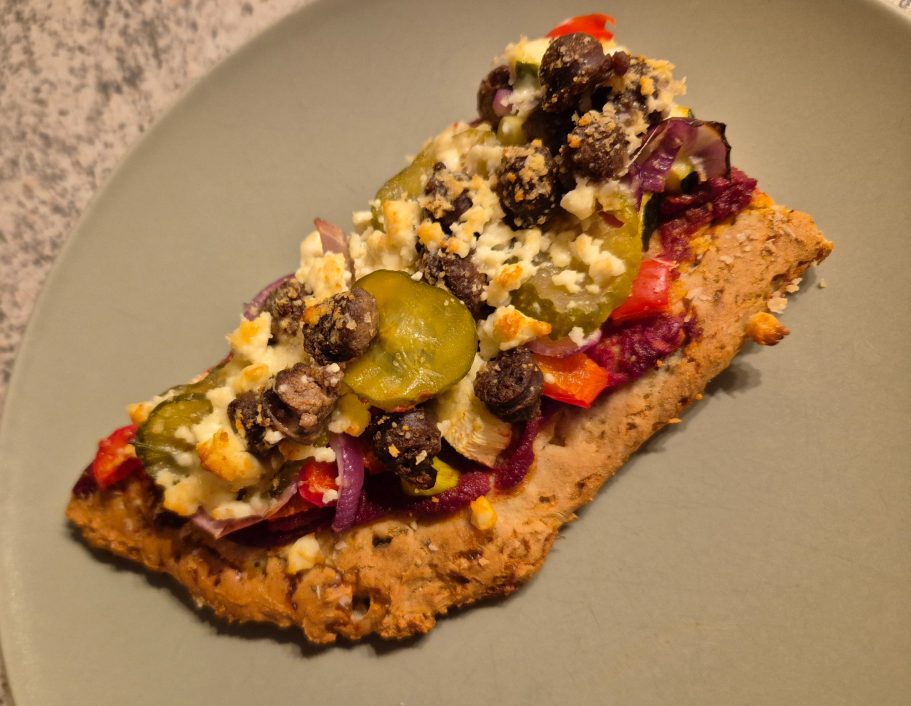 selbstgemachte, glutenfreie Pizza aus Buchweizenmehl belegt mit eigens hergestellter Tomatensauce, Bratwurst vom Weiderind, Feta, etc.